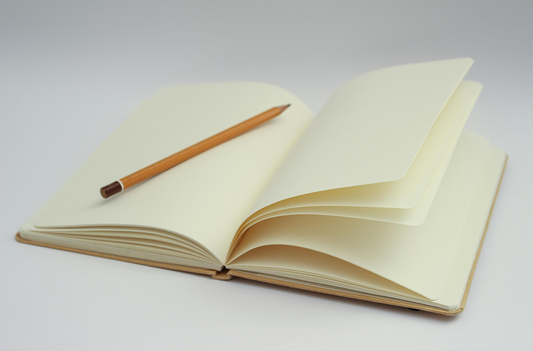 clean journal with blank white pages and yellow pencil resting on top on a white background