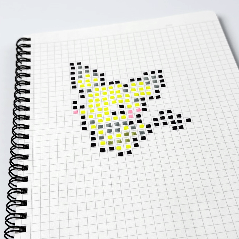 close of dot e pixel art pen from sun star stationery creating a yellow and black pichu pikachu sprite with real life pixel art on notebook